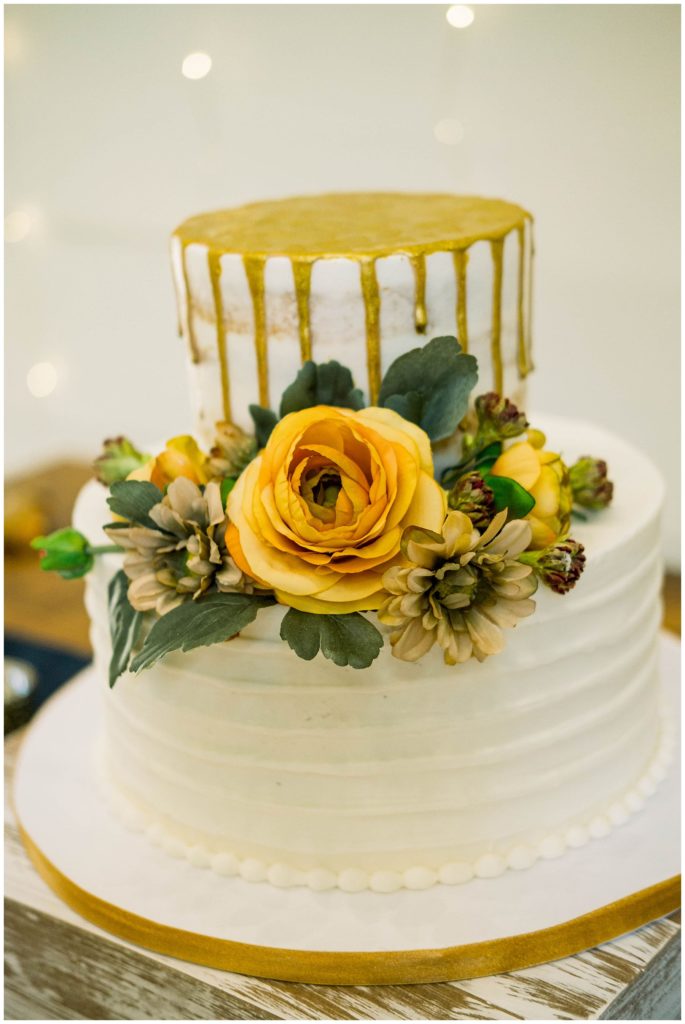 wedding cake with gold accents and yellow florals