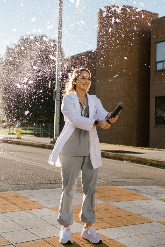 young woman graduating nursing school popping confetti cannon