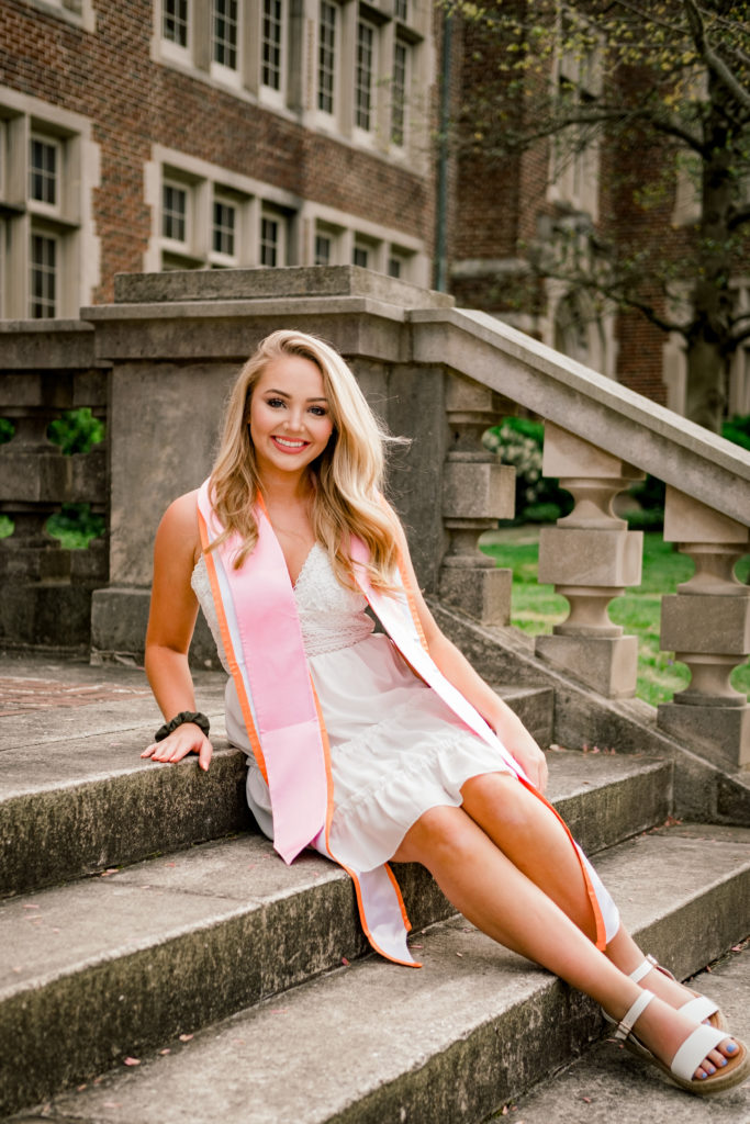 young woman sitting on steps at university of tennessee knoxville celebrating