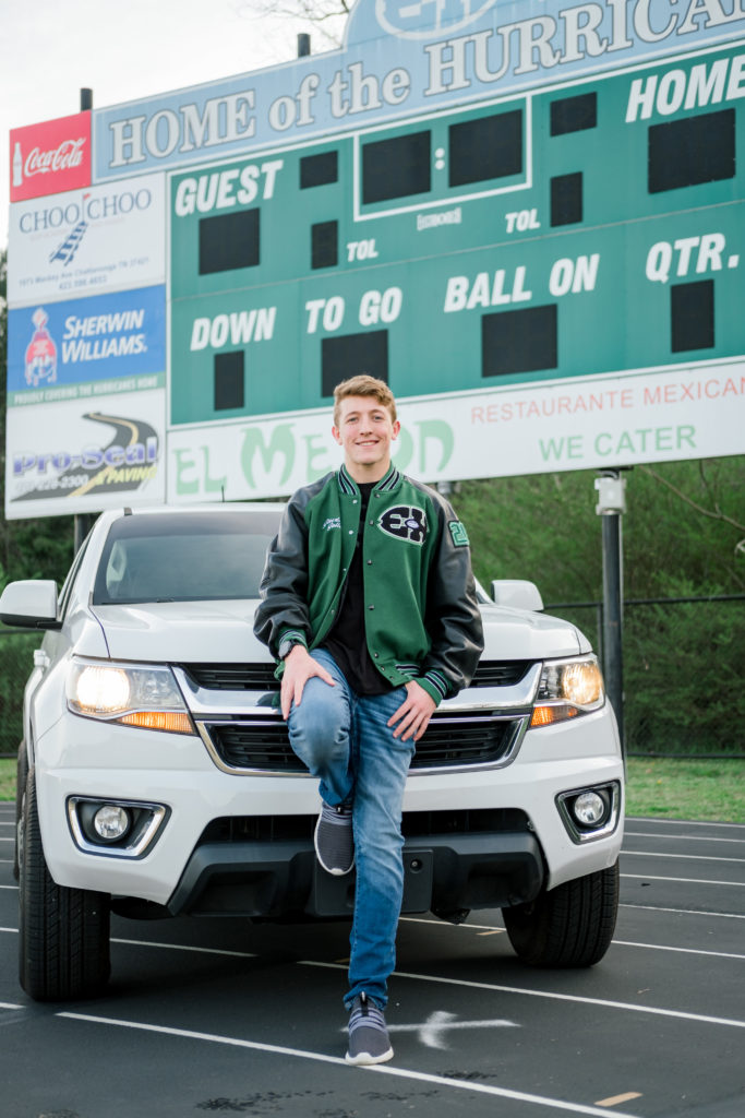 Young high school senior standing in front of his car during outdoor senior session