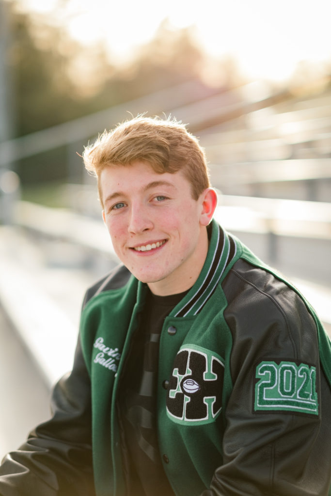 young high school football player wearing leatherman jacket smiling at camera