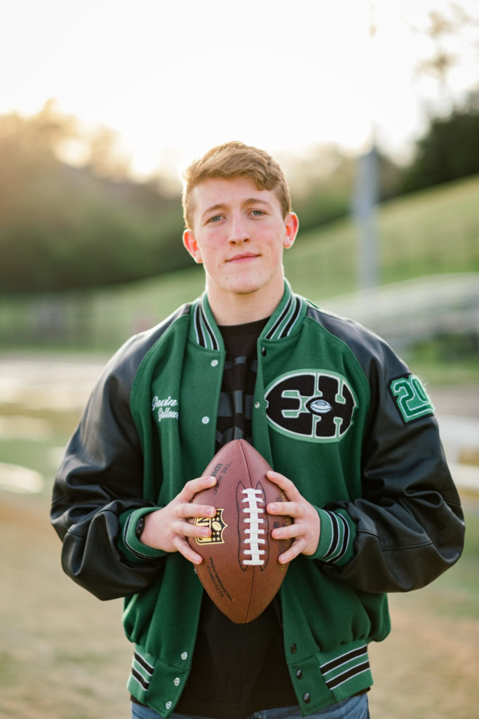 high school senior wearing leathermen's jacket holding football