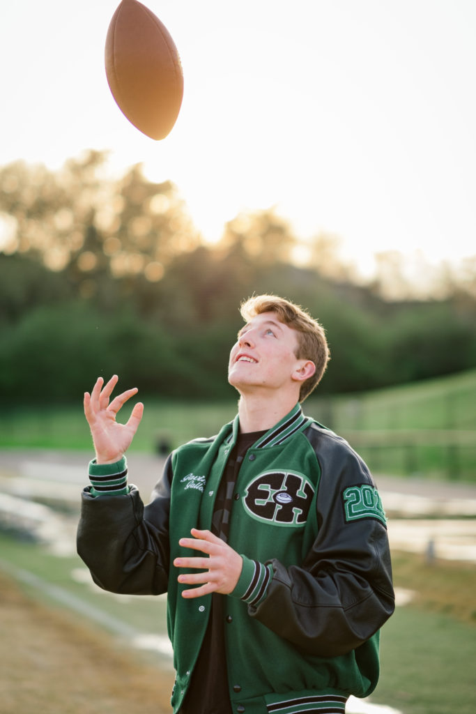 high school football player throws ball in air during senior session