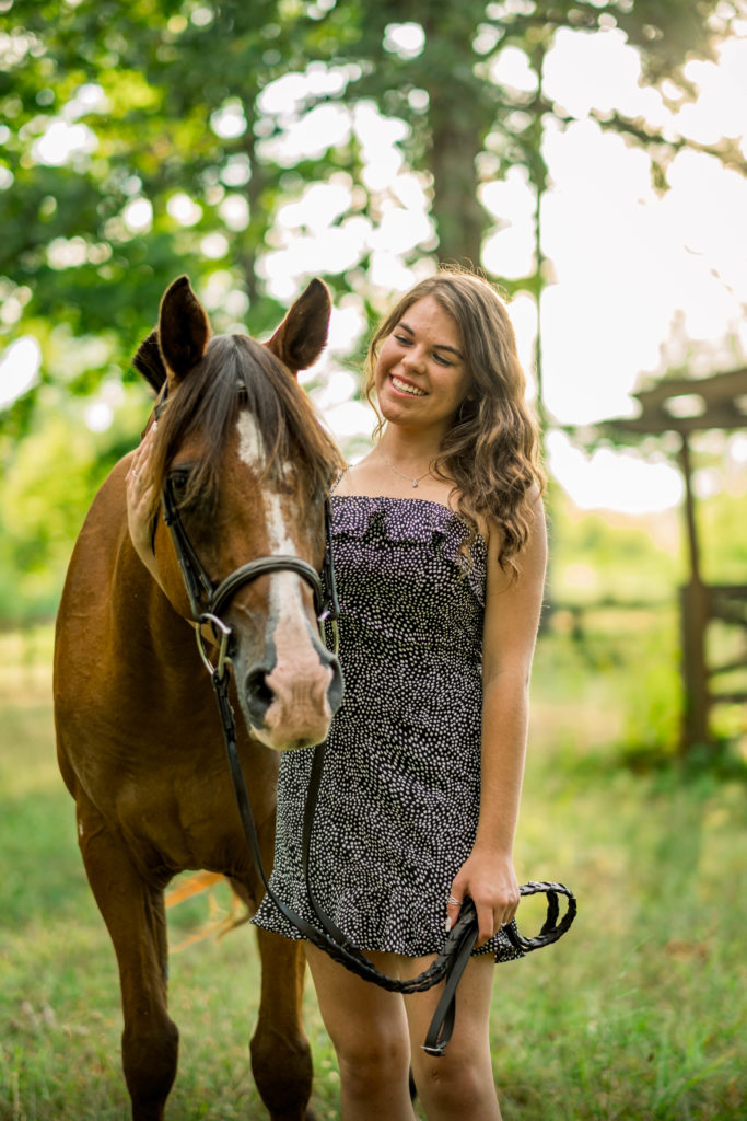 high school senior posing with horse during outdoor session
