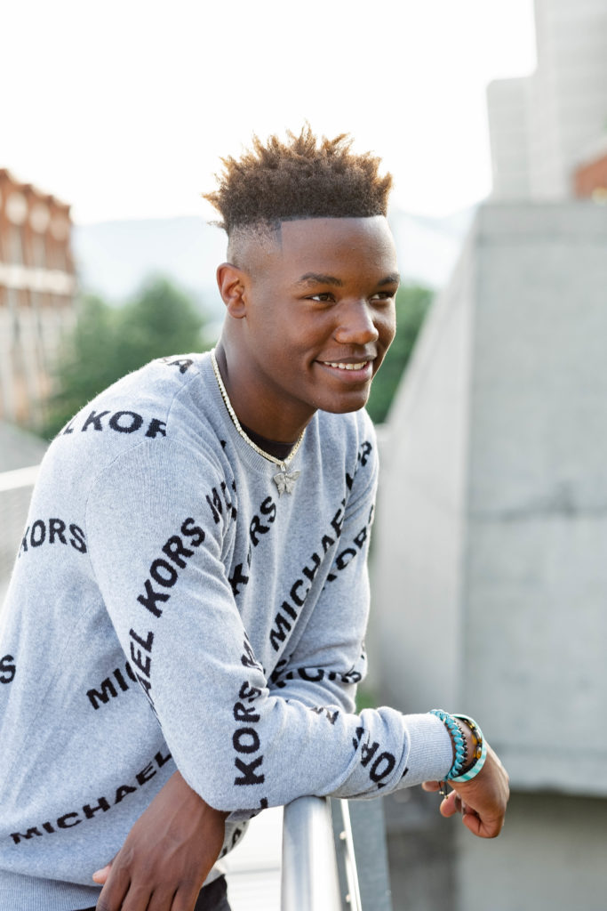 young man smiling wearing a gray sweater during downtown chattanooga senior session
