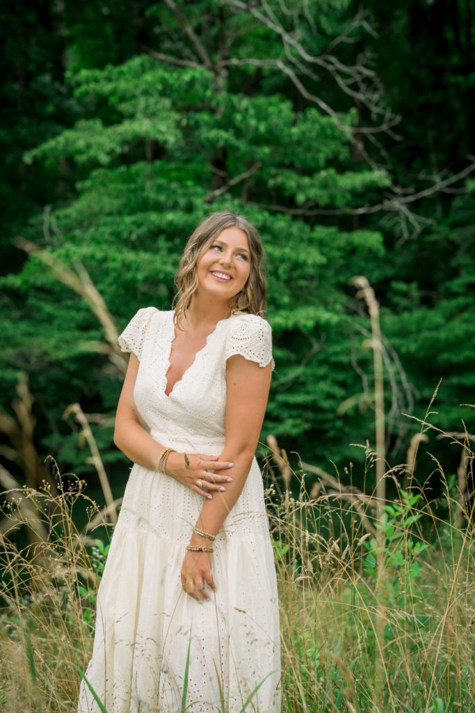 girl laughing in a field in Knoxville Tennessee for her high school senior photos with the best knoxville senior photographers