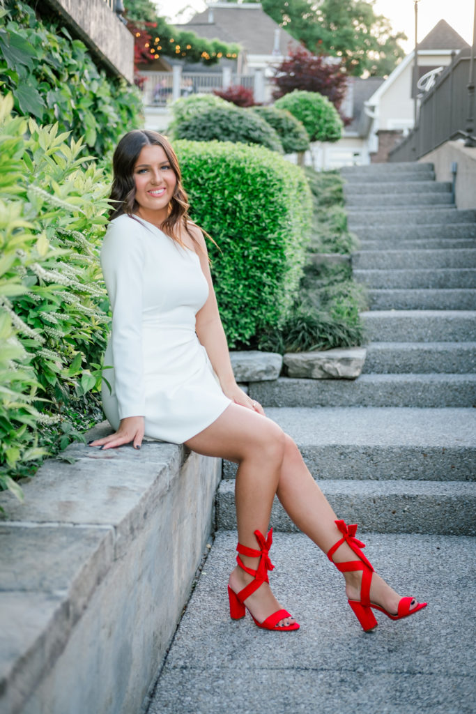 young woman wearing white dress and red shoes during outdoor senior session