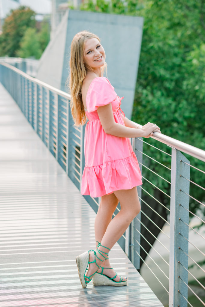 young tennessee senior wearing pink dress smiling on bridge