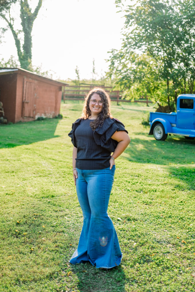 Tennessee senior wearing flare jeans and black shirt in front of old blue pickup truck during Chickamauga Battlefield Outdoor Session 