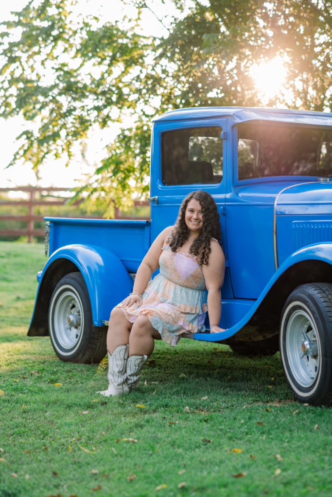 young woman sitting on truck during senior pictures