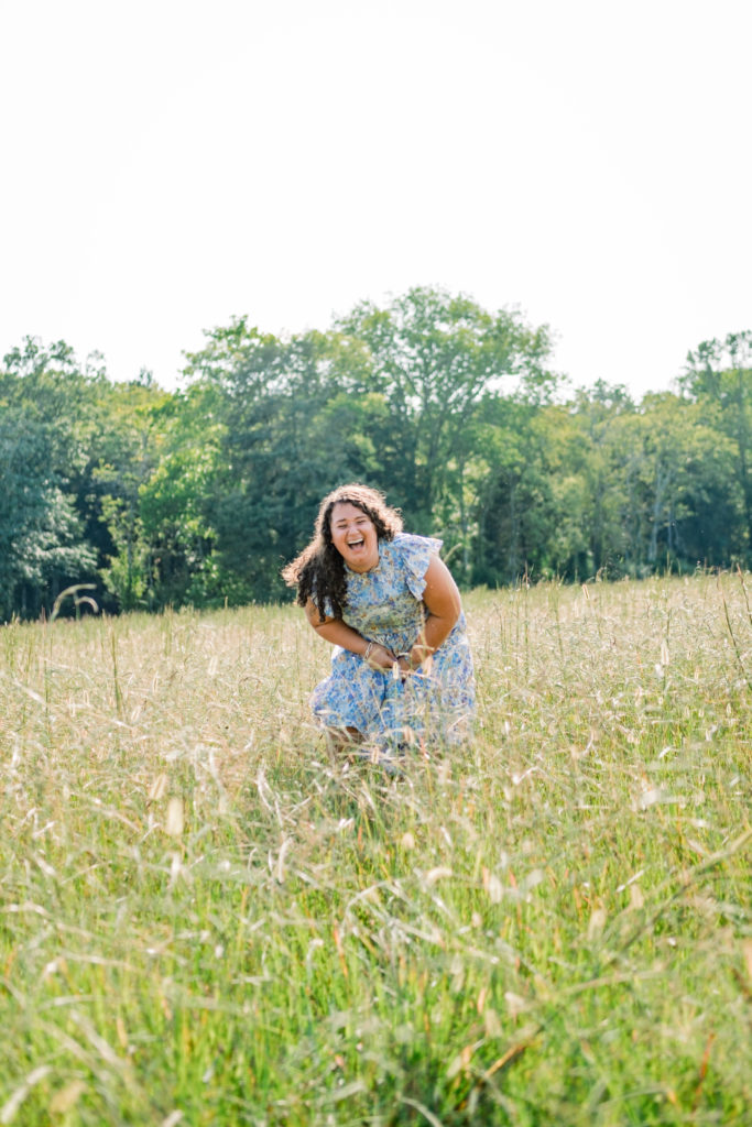 woman laughing in field wearing blue dress