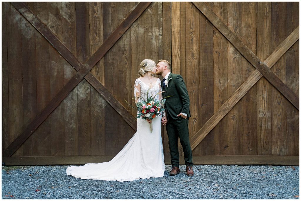 bride and groom kissing in front of hidden springs venue barn after wedding ceremony in Tennessee