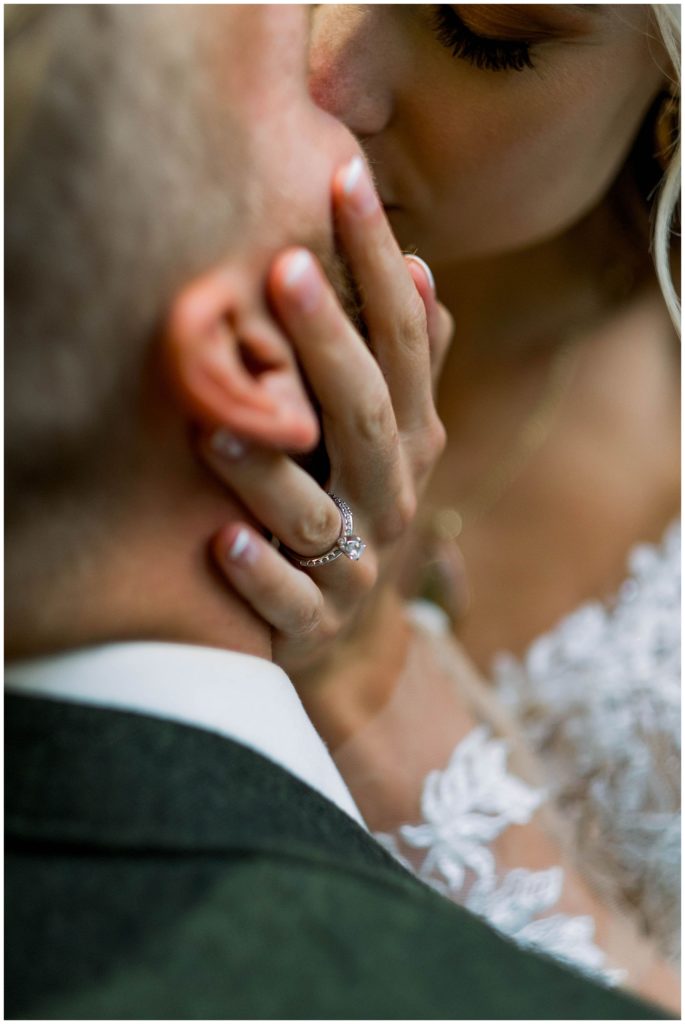 bride holding groom's face and kissing during bridals