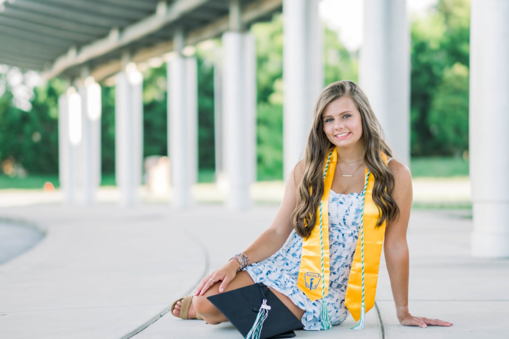 girl sitting on ground wearing graduation clothing