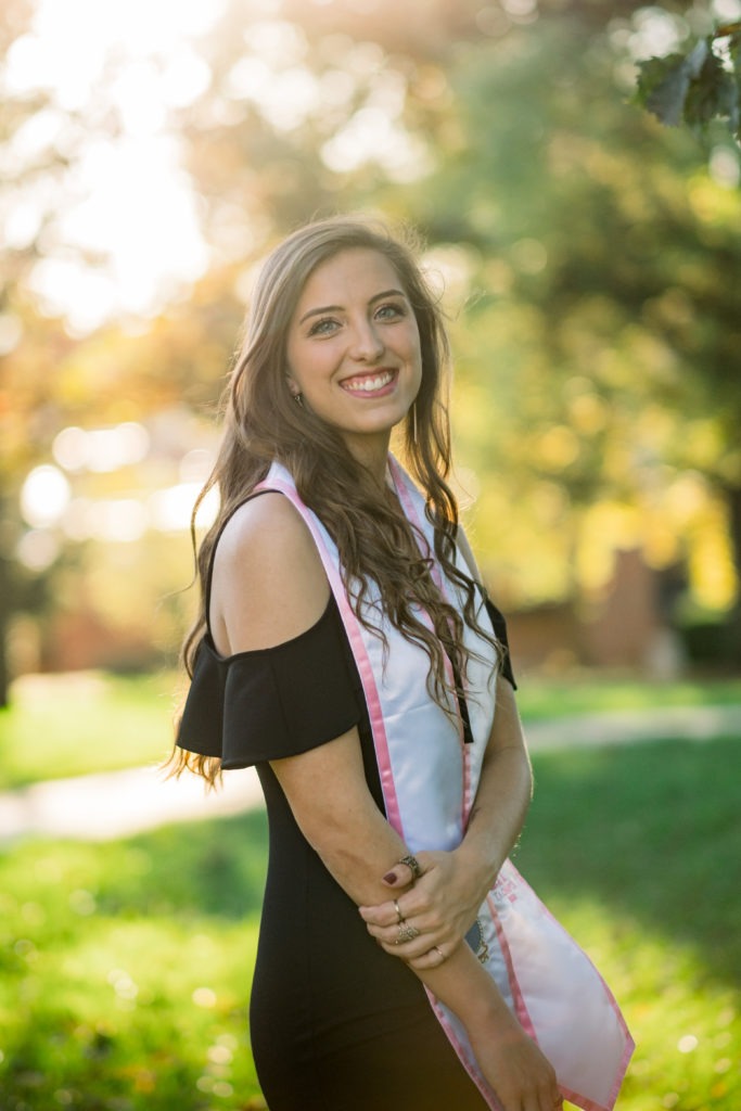 young girl wearing graduation ribbon smiling 