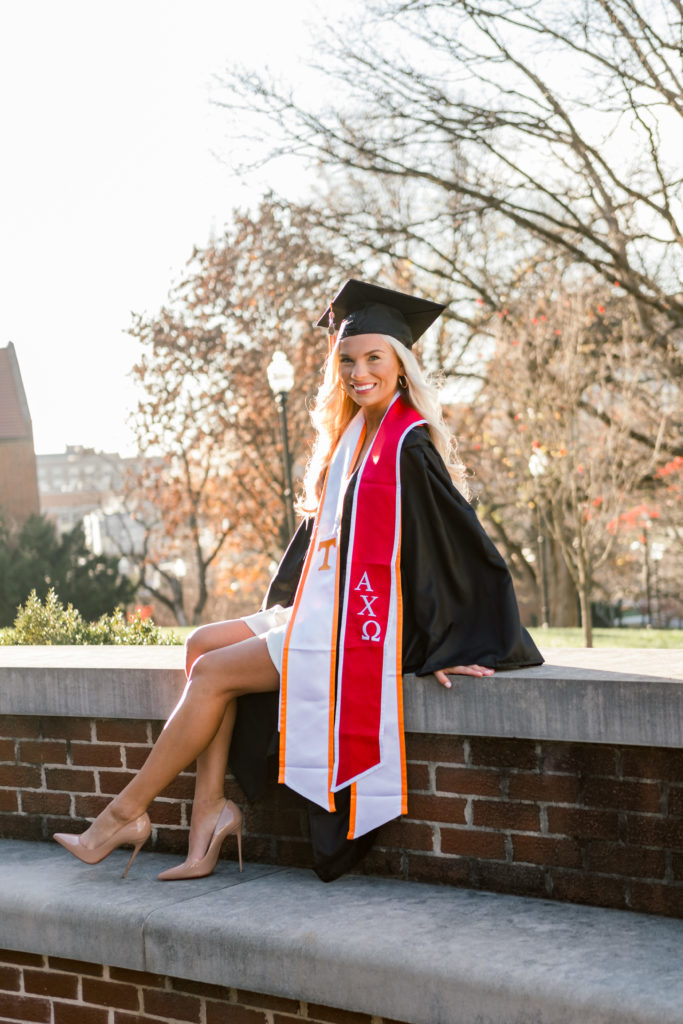 woman sitting on college campus in graduation gown