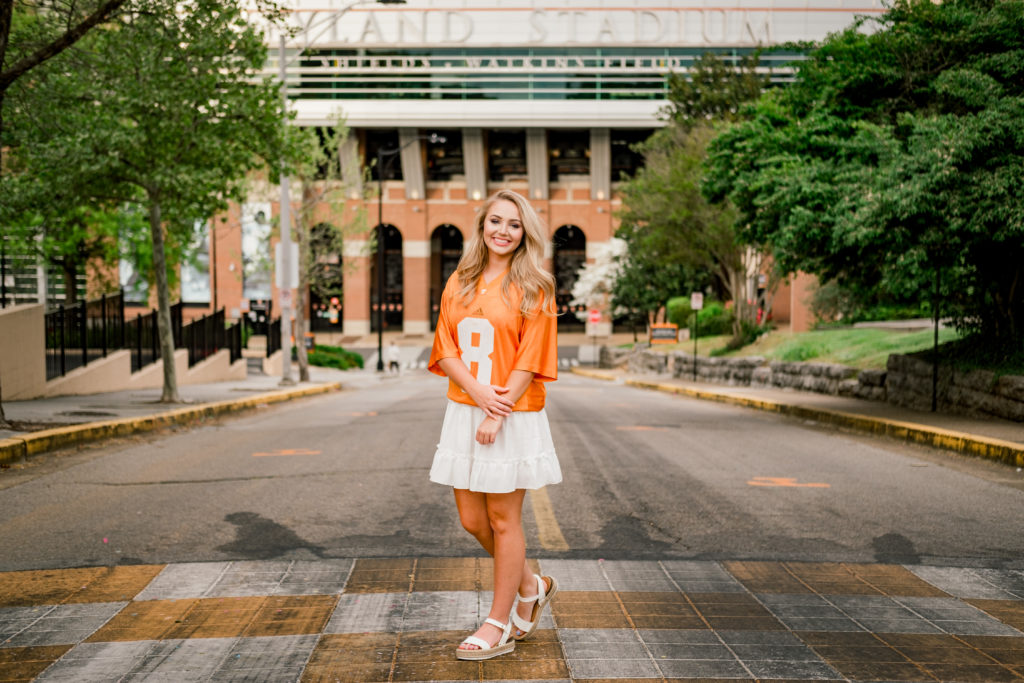 young woman standing on UTK campus in front of stadium celebrating recent graduation