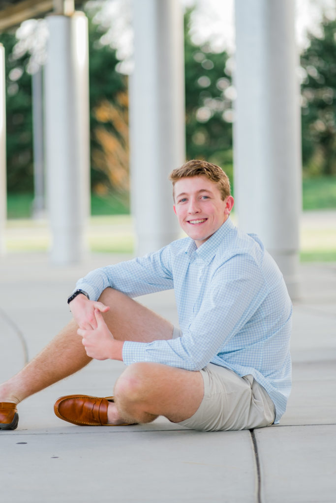 young chattanooga senior sitting on the ground wearing blue shirt during senior session