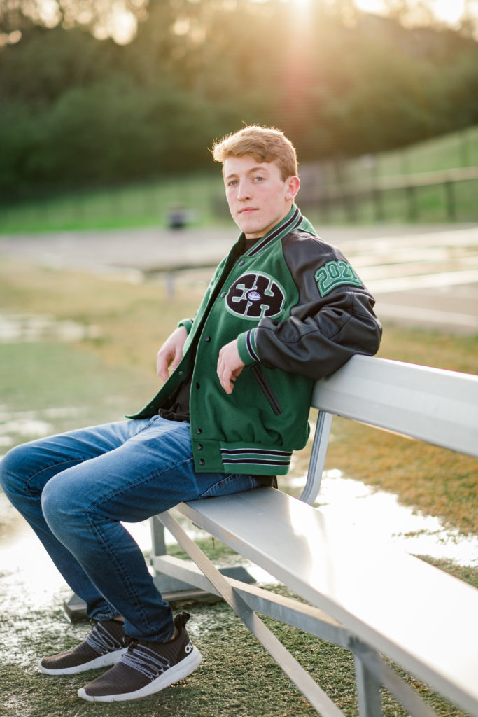 Young man sitting on bench on the football field during senior pics