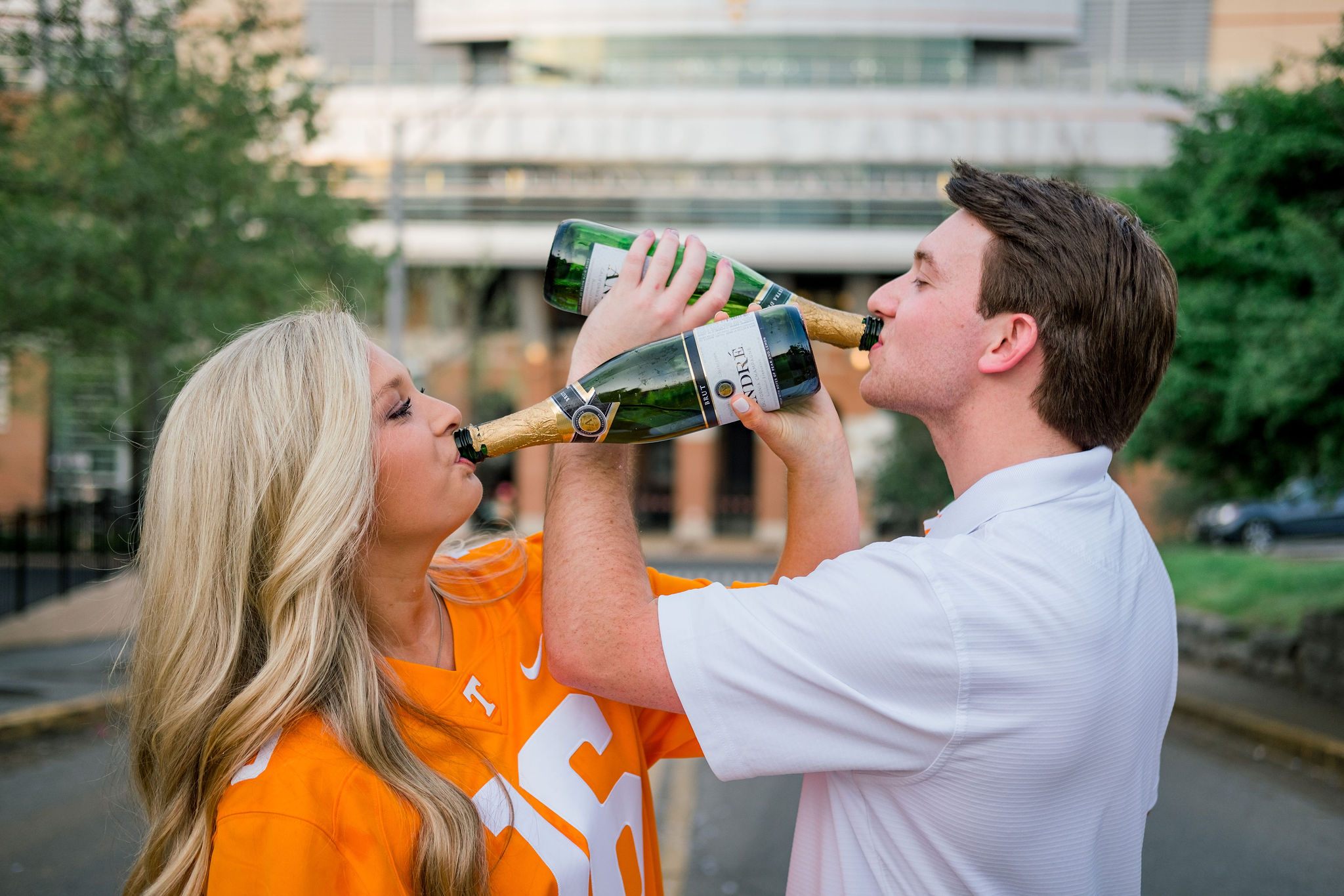 man and woman celebrating recent college graduation drinking champagne together