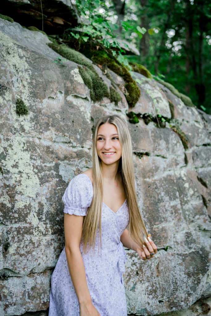young woman standing against rock wall