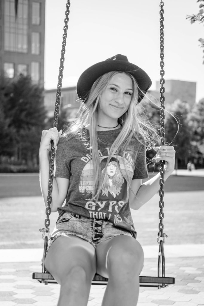 senior sitting on swing wearing graphic tee and hat during chattanooga outdoor senior session