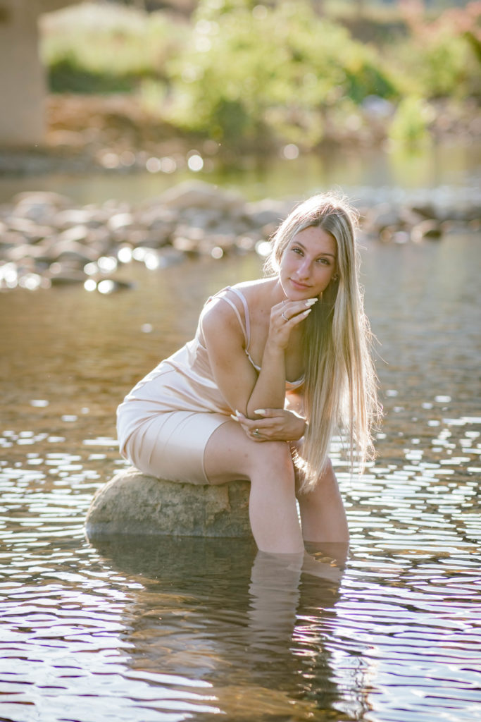 young graduate sitting on rock in creek at Soddy Daisy