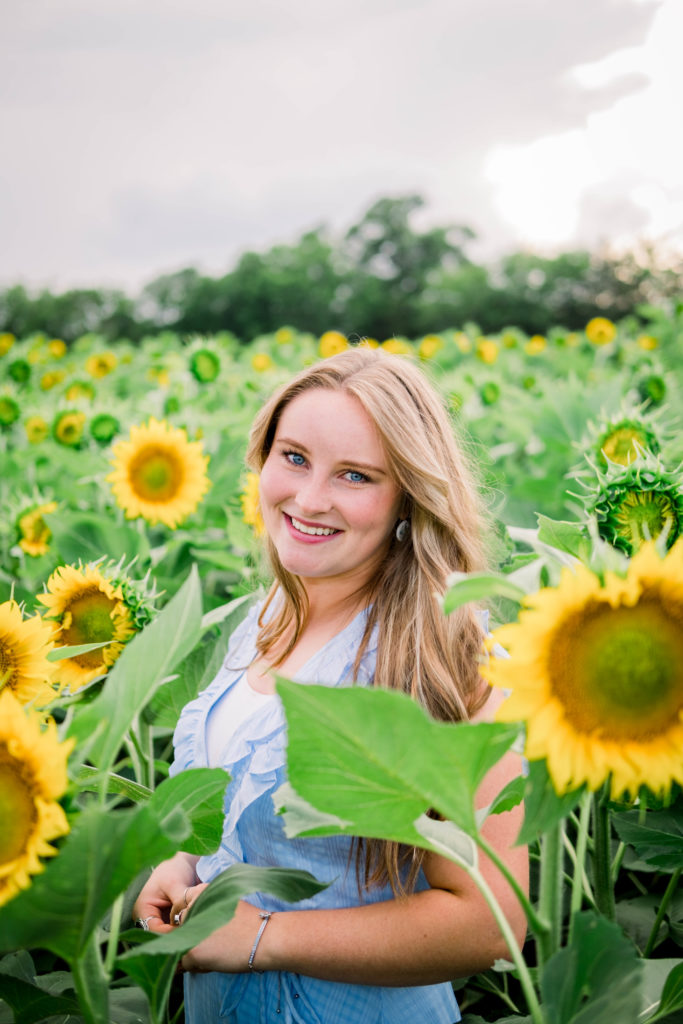 young Tennessee senior smiling while wearing blue dress outdoors in field of flowers
