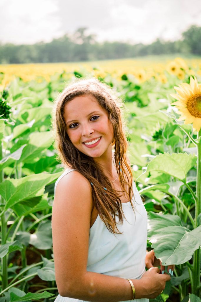 young woman with brown hair smiling at camera during senior portraits session