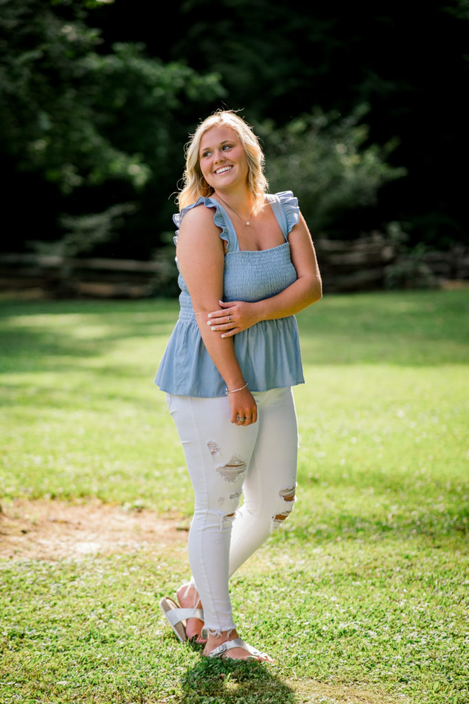 Young tennessee senior wearing blue tank and white pants during outdoor senior portraits