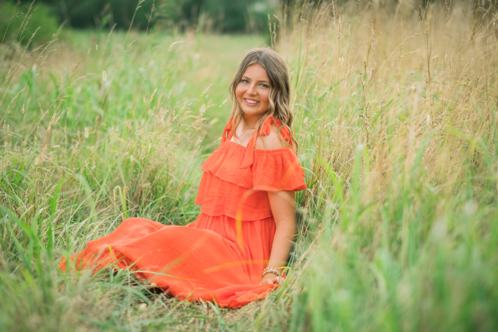Young Knoxville senior posing in orange dress in Chattanooga field
