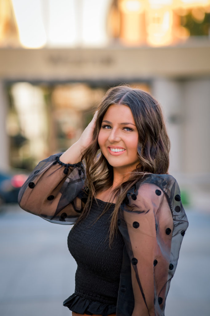 young woman wearing black top smiling during outdoor senior session