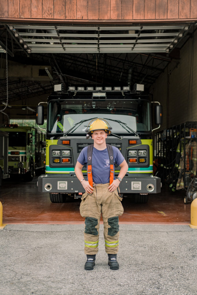 young tennessee senior volunteer firefighter wearing fire gear standing in front of fire truck in Chattanooga
