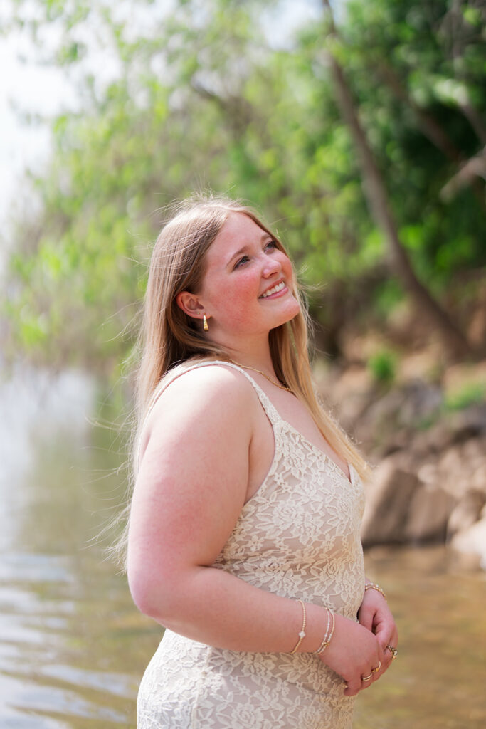 Lauren sitting in the Tennessee River wearing a lace dress | Downtown Chattanooga senior pictures in the river | Bess Pics Photography