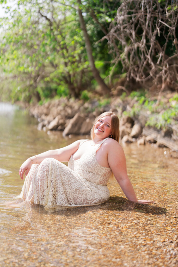 Lauren sitting in the Tennessee River wearing a lace dress | Downtown Chattanooga senior pictures in the river | Bess Pics Photography
